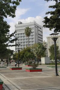 un gran edificio blanco con palmeras en un aparcamiento en Mersin Oteli, en Mersin