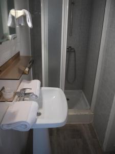 La salle de bains est pourvue d'un lavabo et d'une douche. dans l'établissement Hotel De La Poste, à Ganges
