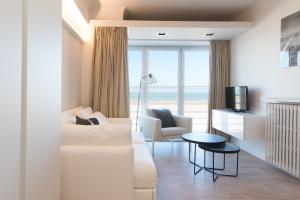 een woonkamer met een witte bank en een tafel bij Ter Duinen in Oostende