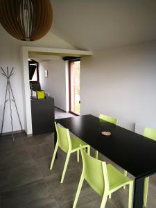 a dining room with a black table and green chairs at Au Simply in Francorchamps