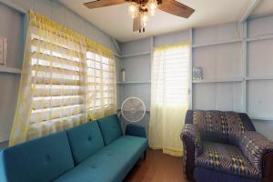 ein Wohnzimmer mit einem blauen Sofa und einem Ventilator in der Unterkunft Carol's Cabanas in Placencia Village