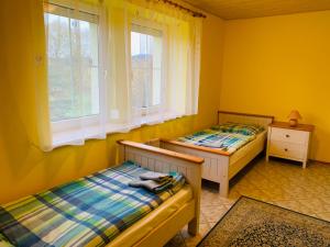 two beds in a room with yellow walls and windows at Penzion Rozalie in Horní Planá