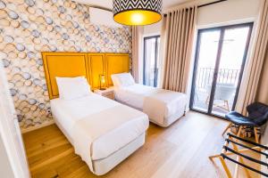 une chambre d'hôtel avec deux lits et une chaise dans l'établissement ALTIDO Bairro Alto 2-BR Apartment with Large Terrace, à Lisbonne
