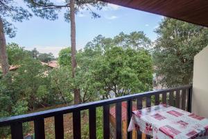 a table on a balcony with a view of trees at Les Genêts in Mimizan-Plage