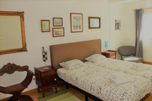 a bedroom with a bed and a mirror and a chair at Apartamento em frente ao Mar in Costa Nova