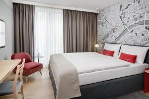 a hotel room with a bed and a red chair at IntercityHotel Frankfurt Hauptbahnhof Süd in Frankfurt/Main