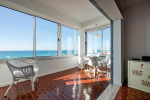 a living room with a table and chairs and the ocean at Ria Beach House By SWEET SPOT FOR US Property Management in Faro