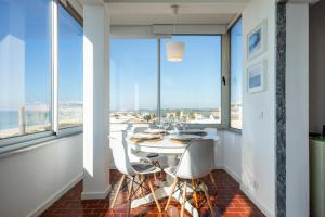 a dining room with a table and some windows at Ria Beach House in Faro