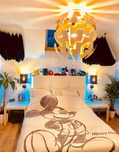 een slaapkamer met een groot bed en een kroonluchter bij Chambres d'hôtes à thèmes à 2,4Km du parc in Magny-le-Hongre