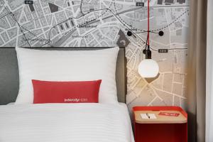 a bedroom with a white bed with a red pillow and a map at IntercityHotel Frankfurt Hauptbahnhof Süd in Frankfurt