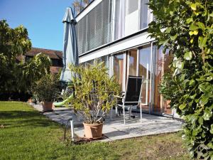 eine Terrasse mit einem Stuhl und einem Sonnenschirm neben einem Haus in der Unterkunft Ferienwohnung Koch Thurgauer Weg in Reichenau