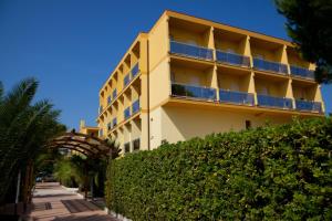 un gran edificio amarillo con arbustos delante de él en Hotel Vittoria, en Vasto