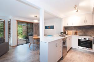 a kitchen with white cabinets and a living room at Byron Bay Accom Calinda Sol 7 in Byron Bay