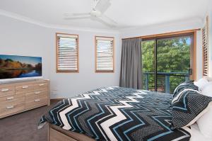 a bedroom with a bed and a tv and a window at Byron Bay Accom Calinda Sol 7 in Byron Bay