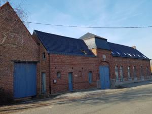 - un grand bâtiment en briques avec des portes et des fenêtres bleues dans l'établissement La Ferme Bleue, à Tournai