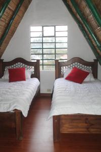 two beds in a room with two red pillows at Chalet Guatavita - Tominé. La Casa Amarilla in Guatavita