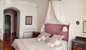 a bedroom with a canopy bed with pink pillows at Villa Antumalal B&B in Málaga