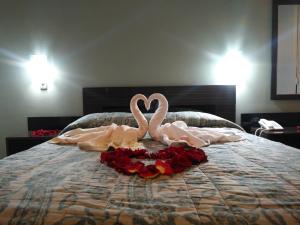 zwei rosa Schwäne auf einem Bett mit Rosen in der Unterkunft Hostal Costa De Marfil Suites & Apartamentos in Cochabamba