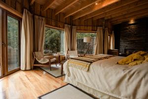 a bedroom with a bed and a desk and a window at Huilo Huilo Nawelpi Lodge in Huilo Huilo +30 photos