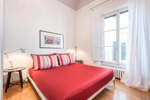 Cama roja en habitación blanca con ventana en Design Apartments Florence- Florence City Center, en Florencia