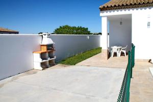 un patio trasero con una valla blanca, una mesa y sillas en Chalet Arroyo Peñuelas 41, en Conil de la Frontera