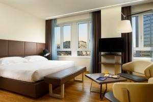a hotel room with a bed and a tv at UNA Hotels Century Milano in Milan +22 photos