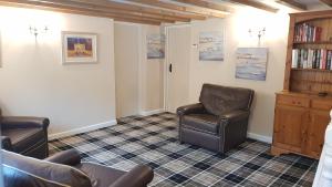 a waiting room with two chairs and a book shelf at Vineyard Vale Cottage in Saundersfoot