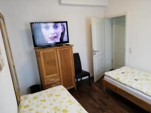 a room with a tv on a dresser with a bed at Isenburger Hof in Neu Isenburg