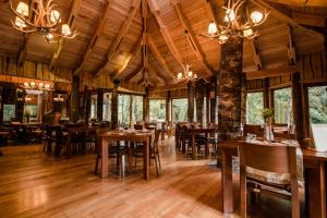 a restaurant with wooden tables and chairs and chandeliers at Huilo Huilo Nawelpi Lodge in Huilo Huilo