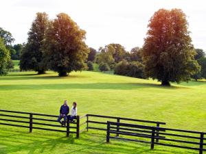 a man and woman sitting on a fence in a field at Lyrath Estate in Kilkenny