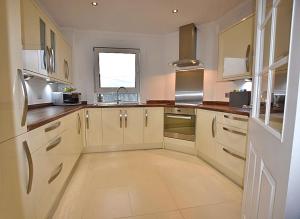 a large kitchen with white cabinets and a window at 12 Lochiel Road in Fort William