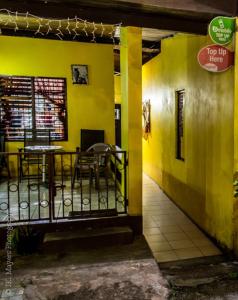 un restaurant avec des murs jaunes, une table et des chaises dans l'établissement Tonys Guest House, à Port-d'Espagne