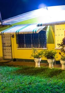 un edificio amarillo con plantas en su interior en Tonys Guest House en Puerto España