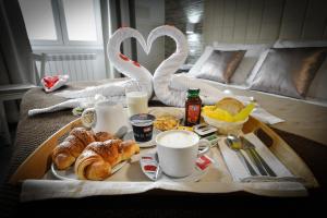 ein Frühstückstablett mit Croissants und Kaffeetassen auf einem Bett in der Unterkunft Domus Castroni Pompeo Magno in Rom
