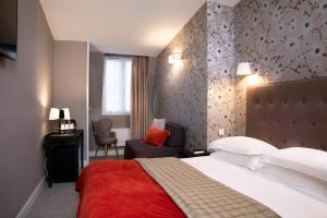 Cette chambre comprend un grand lit et une chaise. dans l'établissement Hôtel Plaza Étoile, à Paris