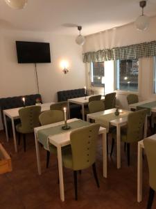 ein Restaurant mit Tischen und Stühlen und einem TV in der Unterkunft Mälarö Hotell in Ekerö