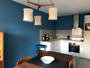a kitchen with a table and a blue wall at Le cabinet de Benoni in Nielles-lès-Bléquin