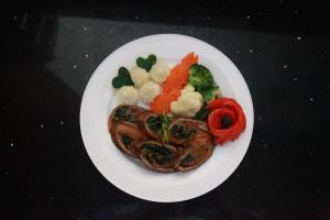 a plate of food with meat and vegetables on a table at Marcen Addis Hotel in Addis Ababa