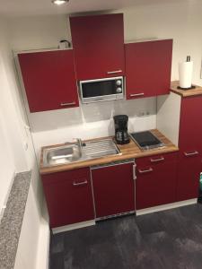 una pequeña cocina con armarios rojos y fregadero en Apartment mit Parkblick, en Tönisvorst