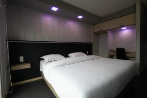 Un dormitorio con una gran cama blanca con dos almohadas. en Hôtel La Rocade, en Pamiers