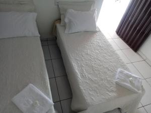 2 camas en una habitación con sábanas y almohadas blancas en Pousada Bela Vista de Mateiros en Mateiros