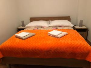 an orange bed with two towels on top of it at Apartment Dada in Bjelovar