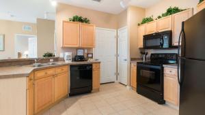 a kitchen with wooden cabinets and black appliances at Disney's Den - Closer to all the fun! in Davenport