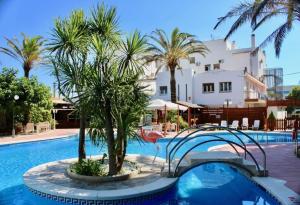 a swimming pool with palm trees in front of a building at Ampuria Inn in Empuriabrava