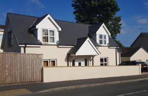 une maison blanche avec un toit noir dans l'établissement Vineyard Vale Cottage, à Saundersfoot