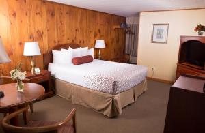 Schlafzimmer mit einem Bett, einem Tisch und einem TV in der Unterkunft Knotty Pine Motel in Bennington