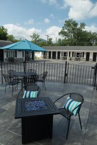 um pátio com mesas e cadeiras e um guarda-sol em Knotty Pine Motel em Bennington