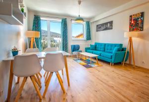 a living room with a blue couch and a table and chairs at Aparthotel Klínovec Views in Loučná pod Klínovcem