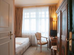ein Hotelzimmer mit einem Bett, einem Stuhl und einem Fenster in der Unterkunft Gästehaus Florian in Tegernsee