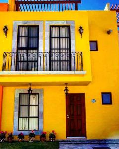 a yellow building with windows and a door at La Rosa House in San Miguel de Allende